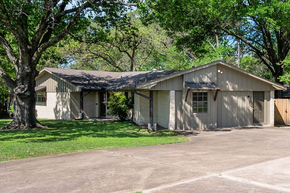 Mid-century home featuring a front yard, brick siding, driveway, and board and batten siding