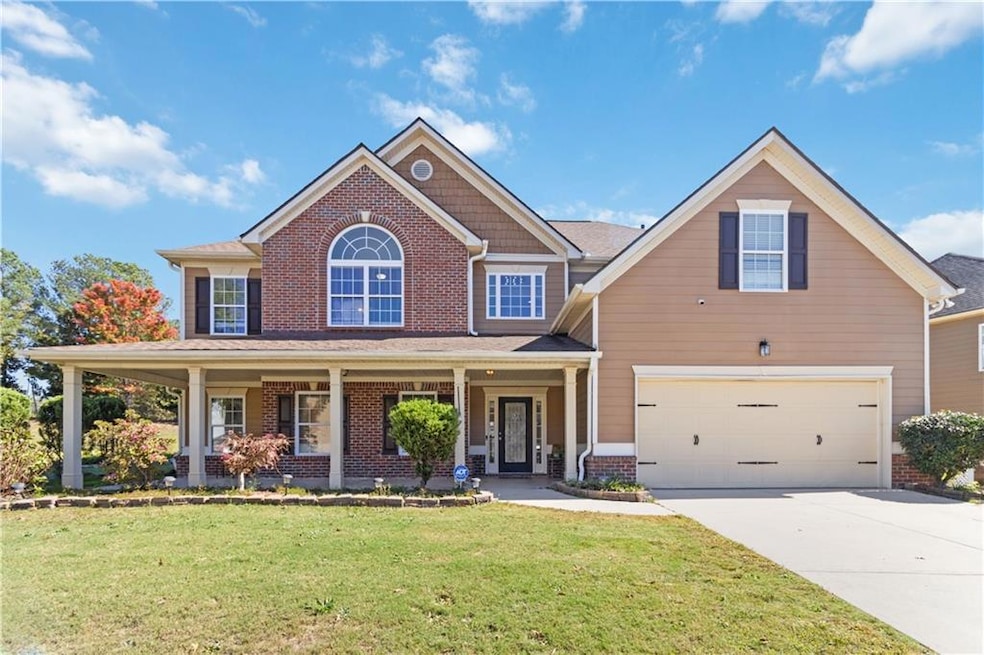 View of front of property featuring a porch, a front lawn, driveway, an attached garage, and brick siding