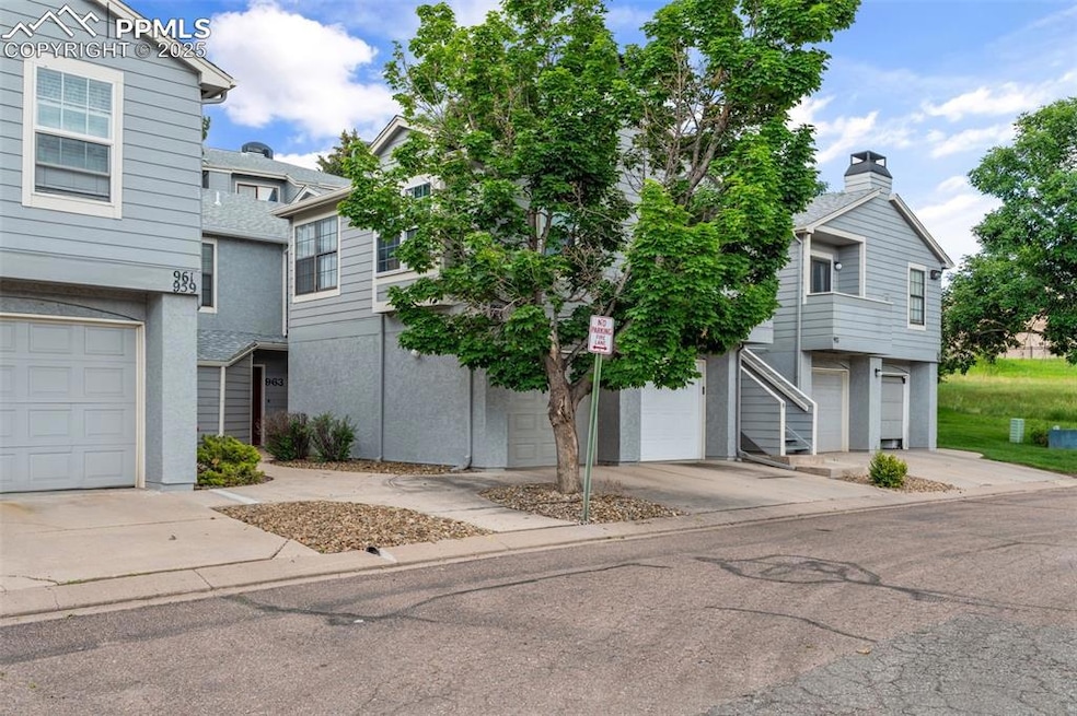 Townhome / multi-family property with driveway, stucco siding, a garage, and a chimney