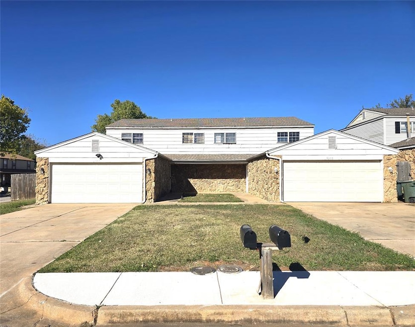 Traditional home with stone siding, driveway, a front lawn, and an attached garage