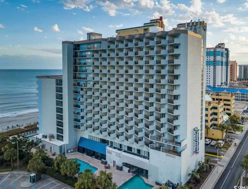 View of building exterior featuring a water view and uncovered parking