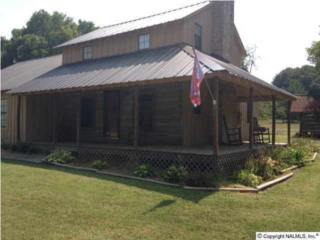 Front view reveals wrap-around porch and metal roof.