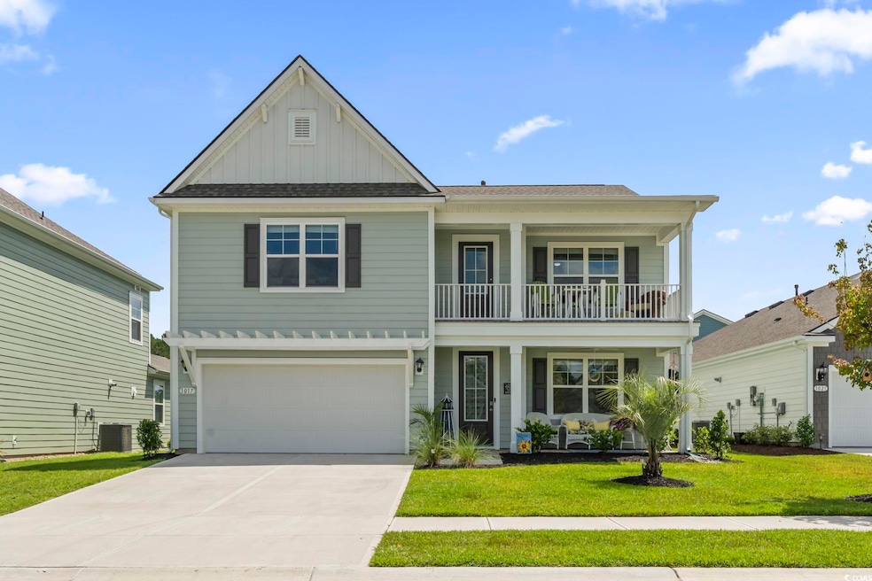 View of front facade featuring board and batten siding, a front yard, an attached garage, concrete driveway, and a balcony