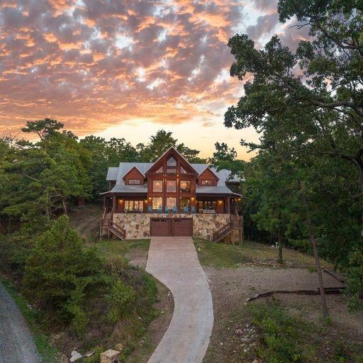 Rustic home featuring stone siding, a garage, concrete driveway, and stairway