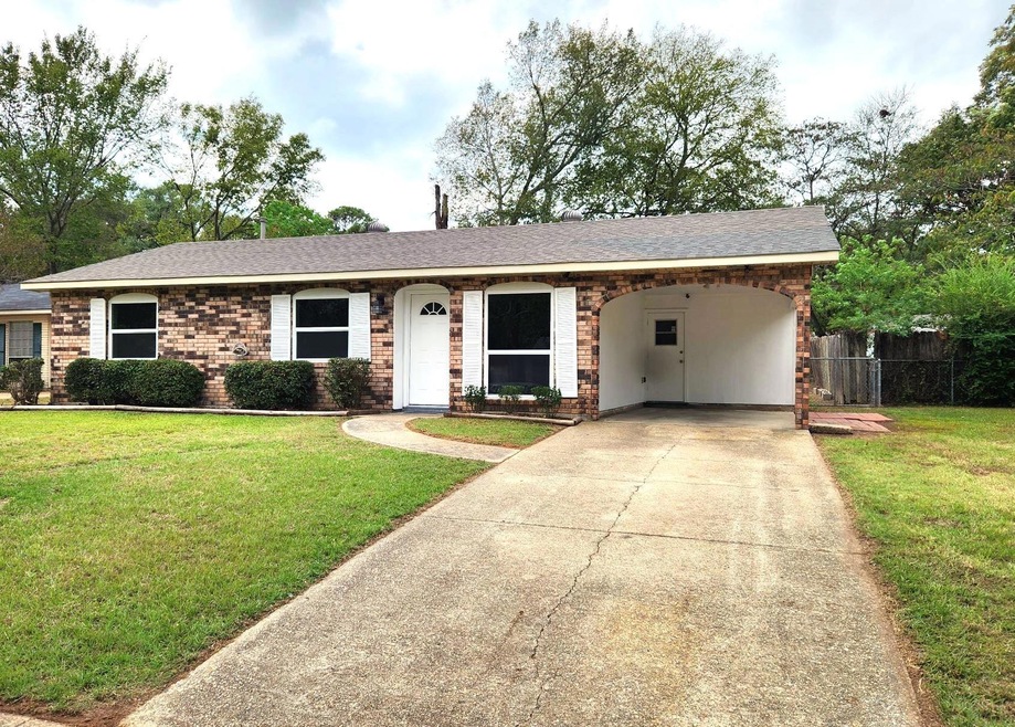 Ranch-style home featuring a carport and a front y