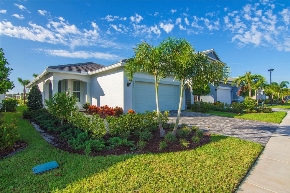 View of property exterior with an attached garage, stucco siding, decorative driveway, and a lawn