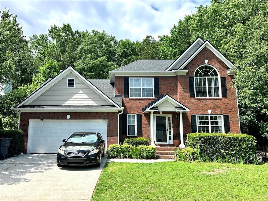View of front of home featuring brick siding, driveway, a front lawn, a garage, and roof with shingles