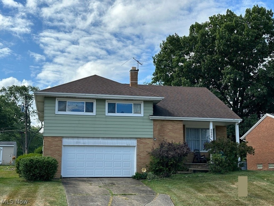 Tri-level home featuring a garage and a front yard