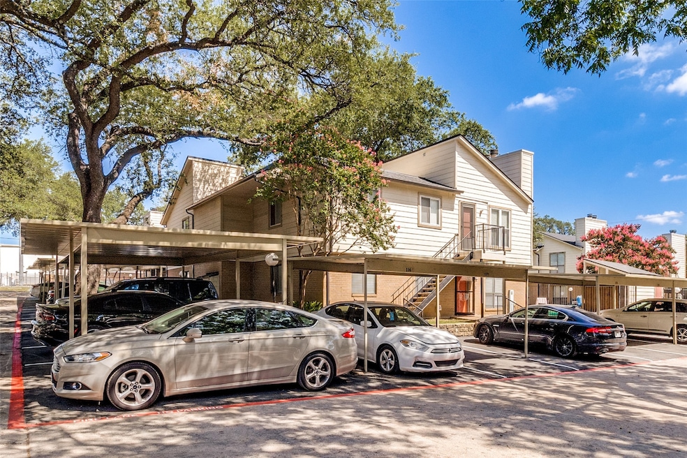 View of front of home with a chimney, covered parking, and stairway