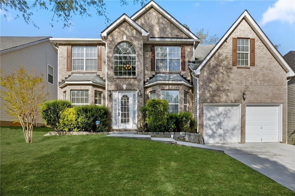 Traditional home featuring driveway, a front lawn, brick siding, and a garage