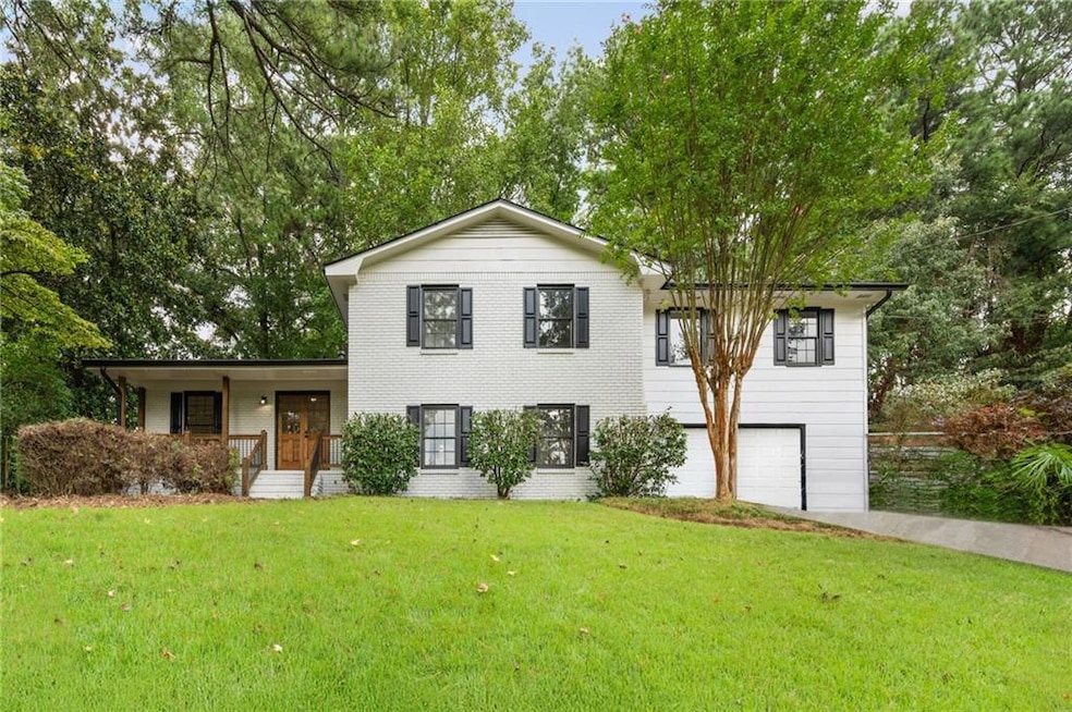 View of front of house featuring an attached garage, a front lawn, and view of scattered trees
