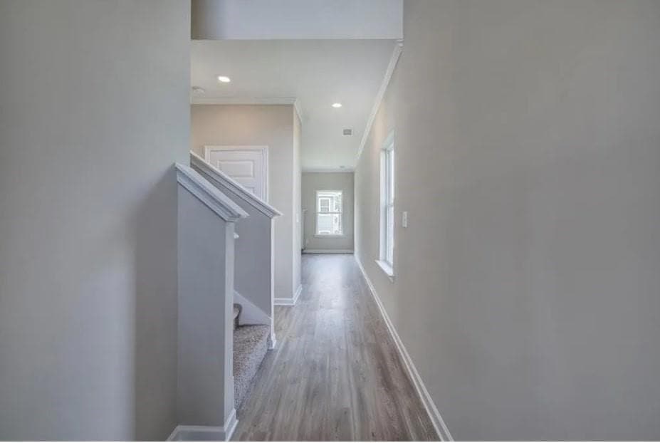Corridor featuring crown molding, stairs, baseboards, wood finished floors, and recessed lighting