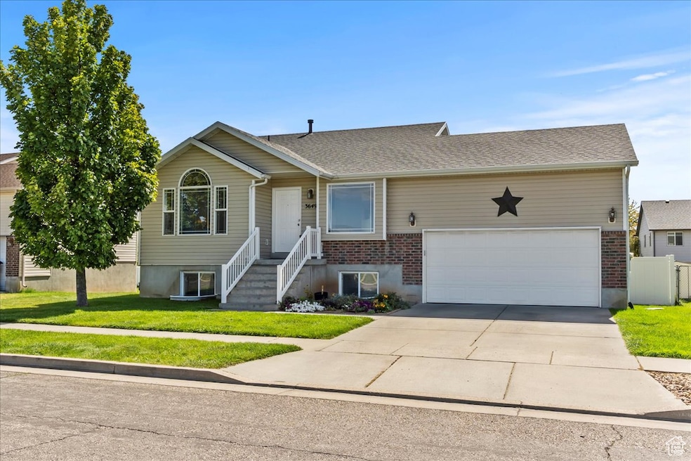 Ranch-style home with a front yard, concrete driveway, brick siding, and an attached garage