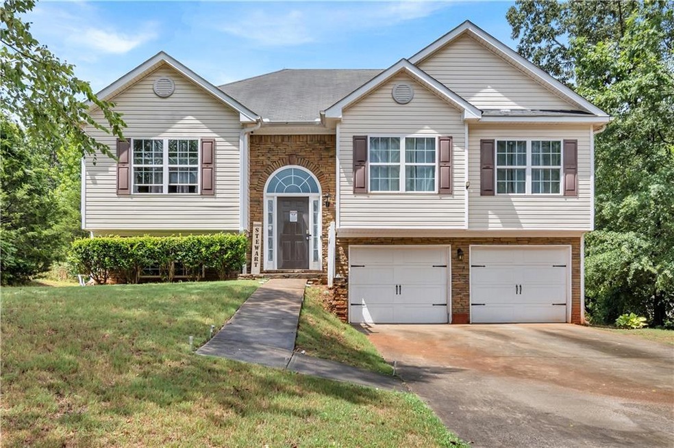 Raised ranch featuring a garage and a front lawn