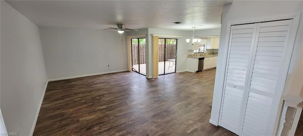 Unfurnished living room with a chandelier, ceiling fan, dark wood-style floors, a sink, and baseboards