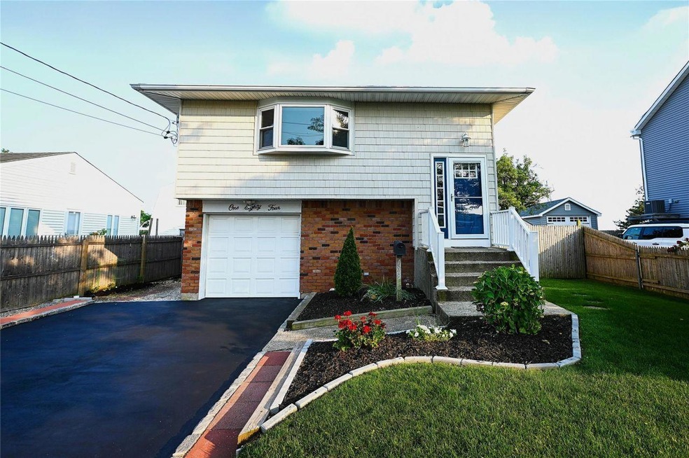 View of front facade with brick siding, driveway, and an attached garage