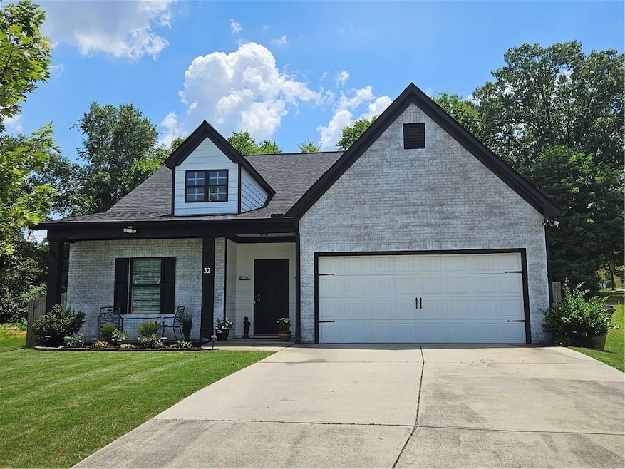 View of front facade with a porch, a front lawn, an attached garage, concrete driveway, and brick siding
