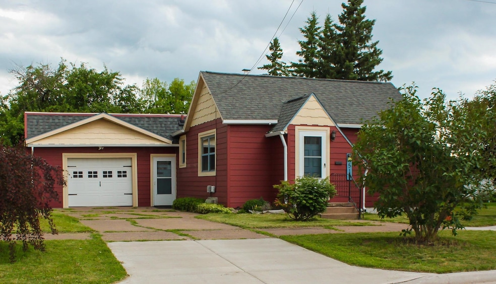 View of front of property featuring driveway, a garage, a shingled roof, and a front yard