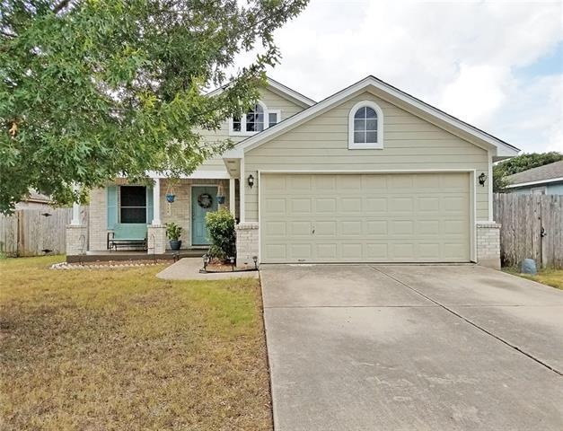 Front of home with large oak tree, garden beds, an