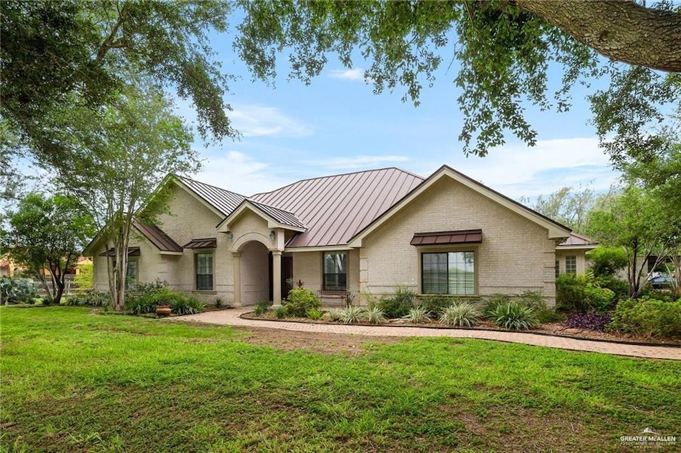 View of front of property with a standing seam roof, a metal roof, a front lawn, and brick siding