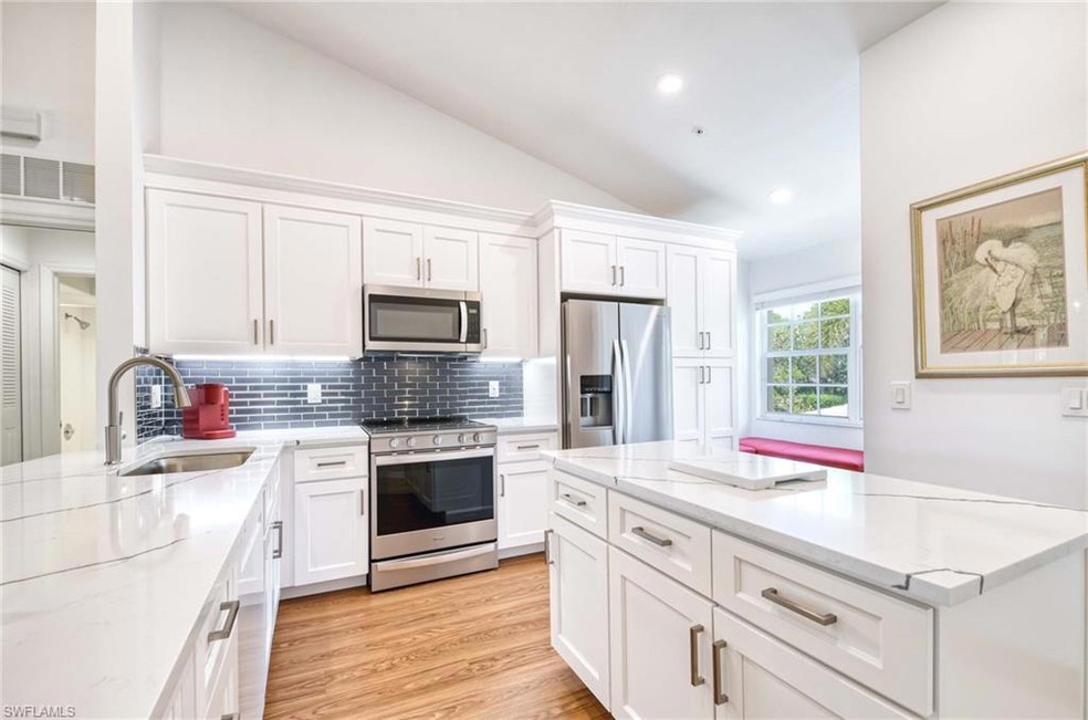 Kitchen featuring vaulted ceiling, white cabinets,