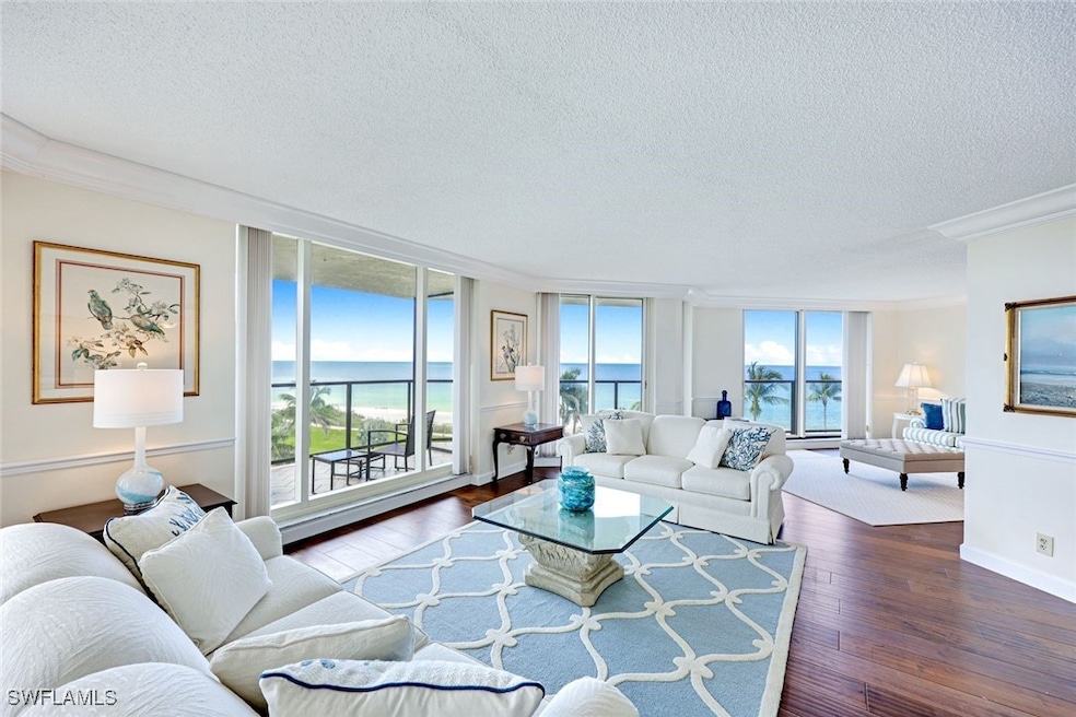Living area featuring crown molding, a textured ceiling, hardwood / wood-style flooring, a wall of windows, and a baseboard radiator