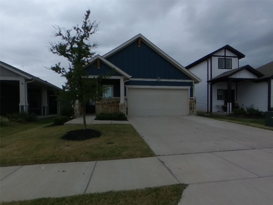 View of front of property with concrete driveway, an attached garage, board and batten siding, and a front yard