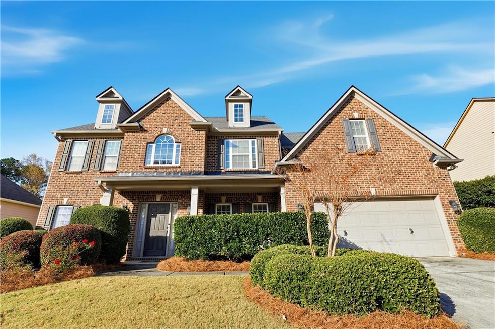 View of front facade with brick siding, driveway, a porch, and a front yard