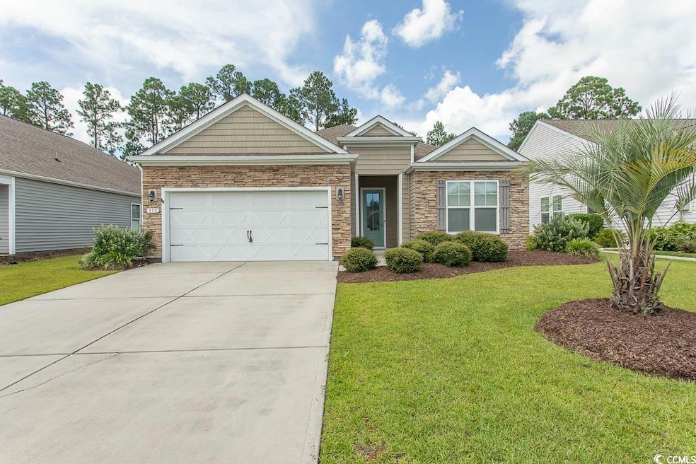 View of front of home with stone siding, a garage, concrete driveway, and a front lawn