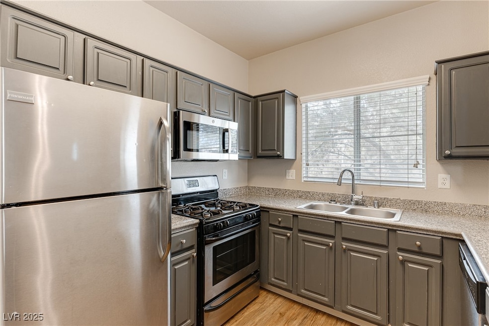 Kitchen featuring gray cabinetry, stainless steel appliances, light wood-style flooring, and light countertops