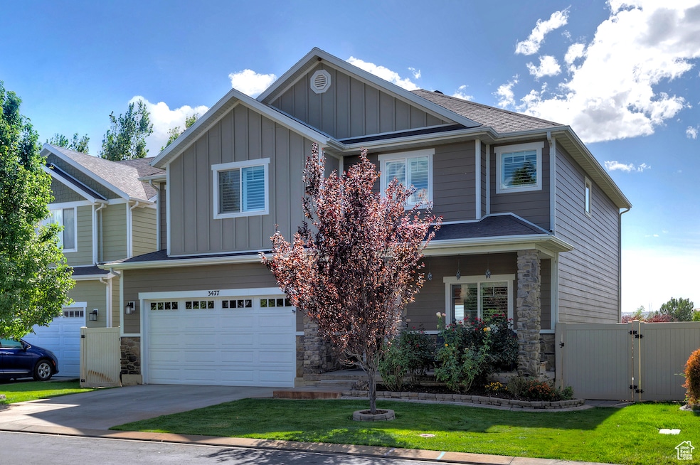 Craftsman-style house with stone siding, board and batten siding, a gate, and an attached garage