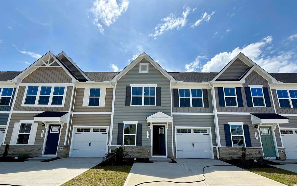 Multi unit property featuring stone siding, driveway, board and batten siding, and a garage