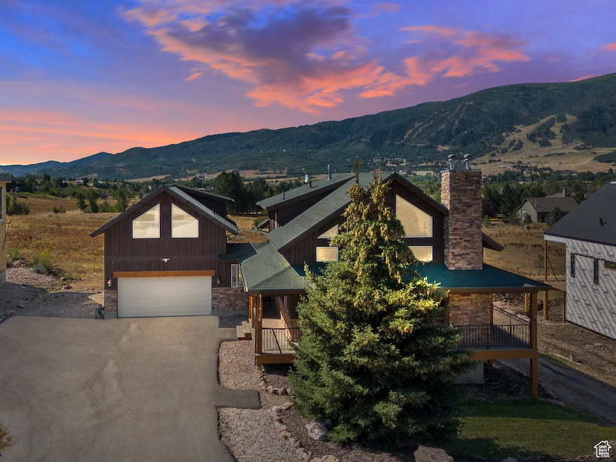 View of front of house featuring a chimney, driveway, a garage, and a mountain view