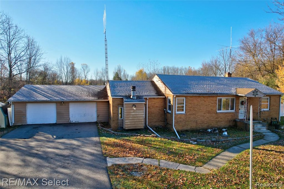 View of front of property with asphalt driveway, a garage, a chimney, and brick siding