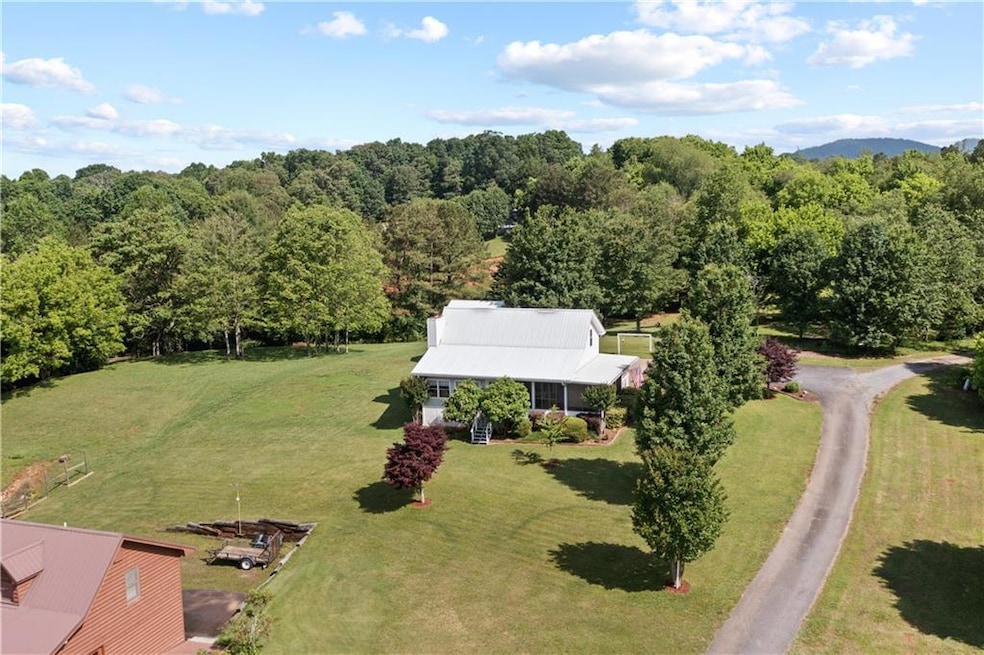 Aerial view of property and surrounding area featuring a forest
