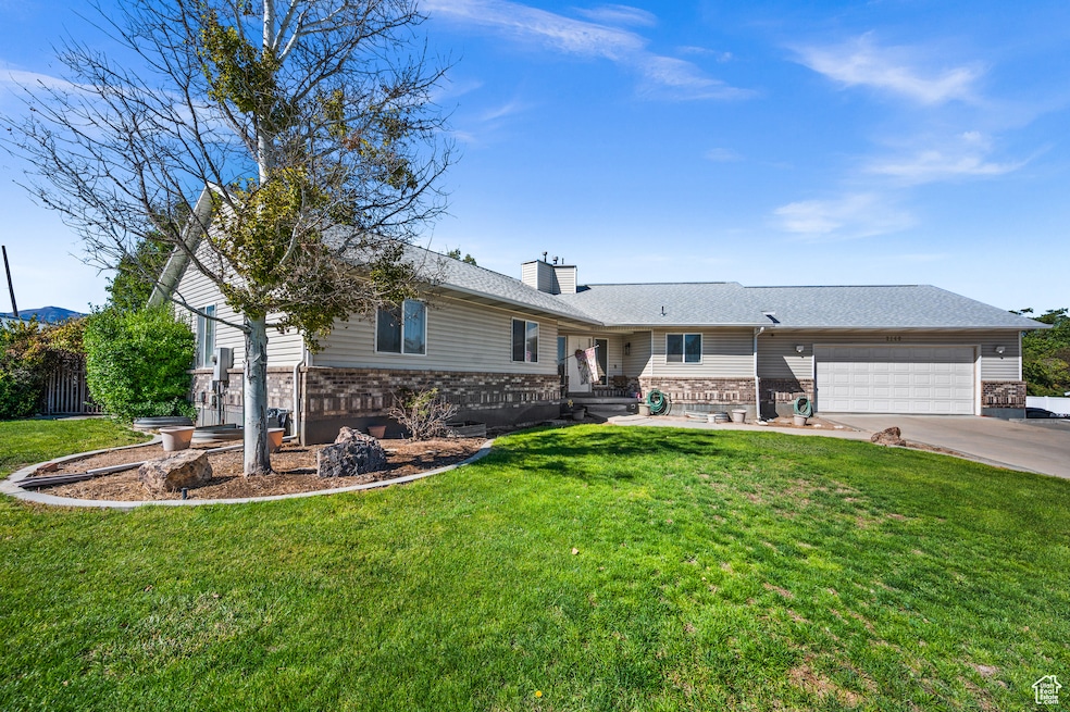 Ranch-style house with a chimney, a front yard, a garage, concrete driveway, and brick siding