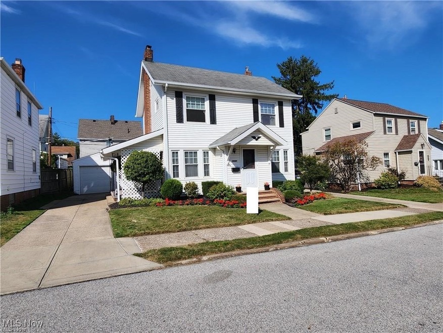 Colonial-style house featuring an outbuilding, a garage, and a front lawn