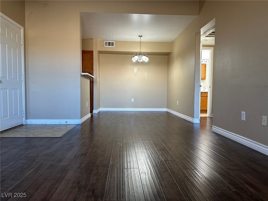 Empty room featuring an inviting chandelier, dark