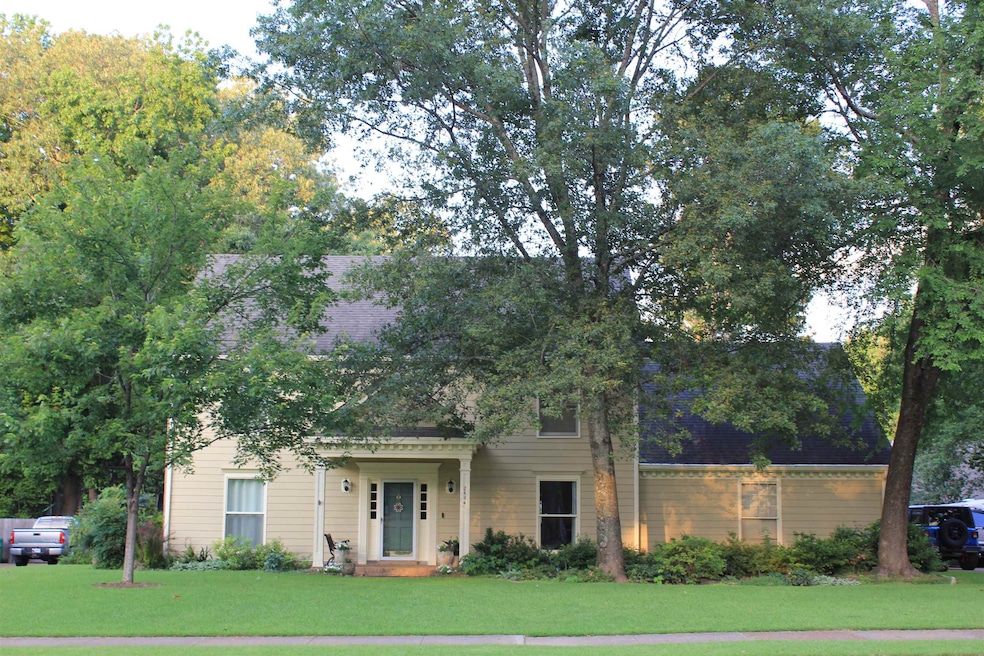 View of property hidden behind natural elements with a front yard