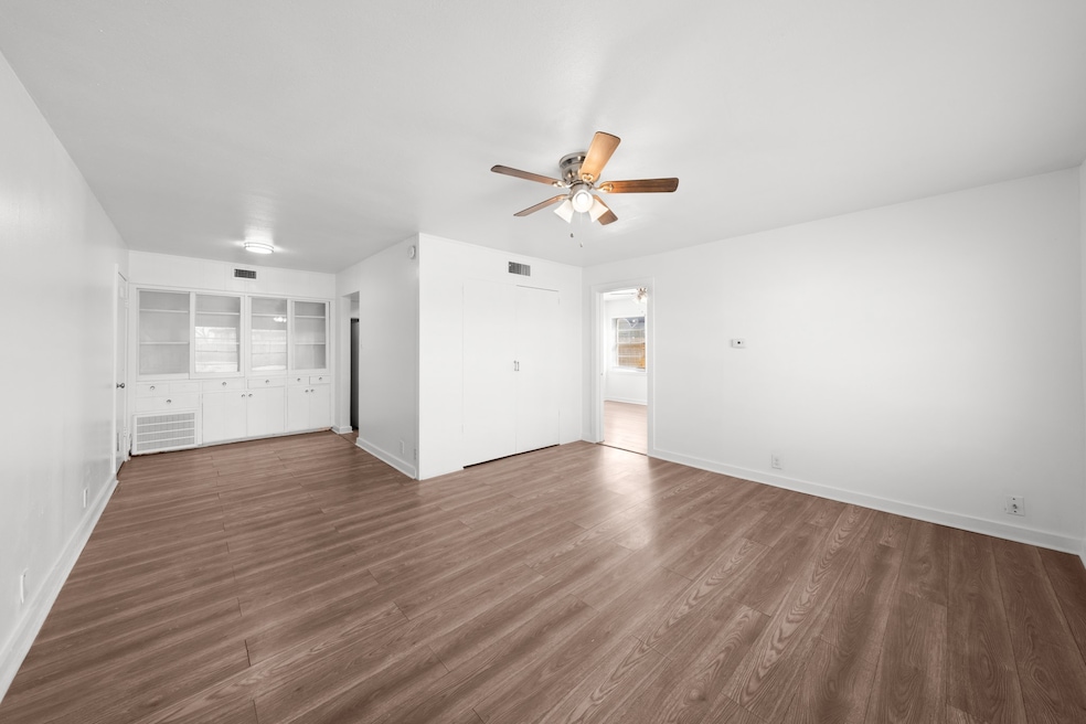 Unfurnished living room featuring dark wood-type flooring and ceiling fan