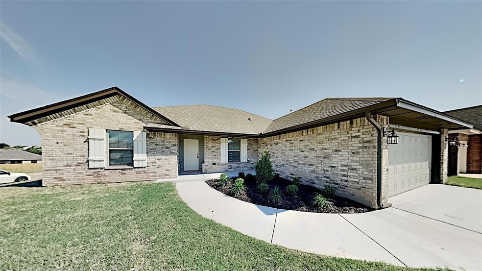 View of front facade featuring brick siding, a garage, a front lawn, and concrete driveway