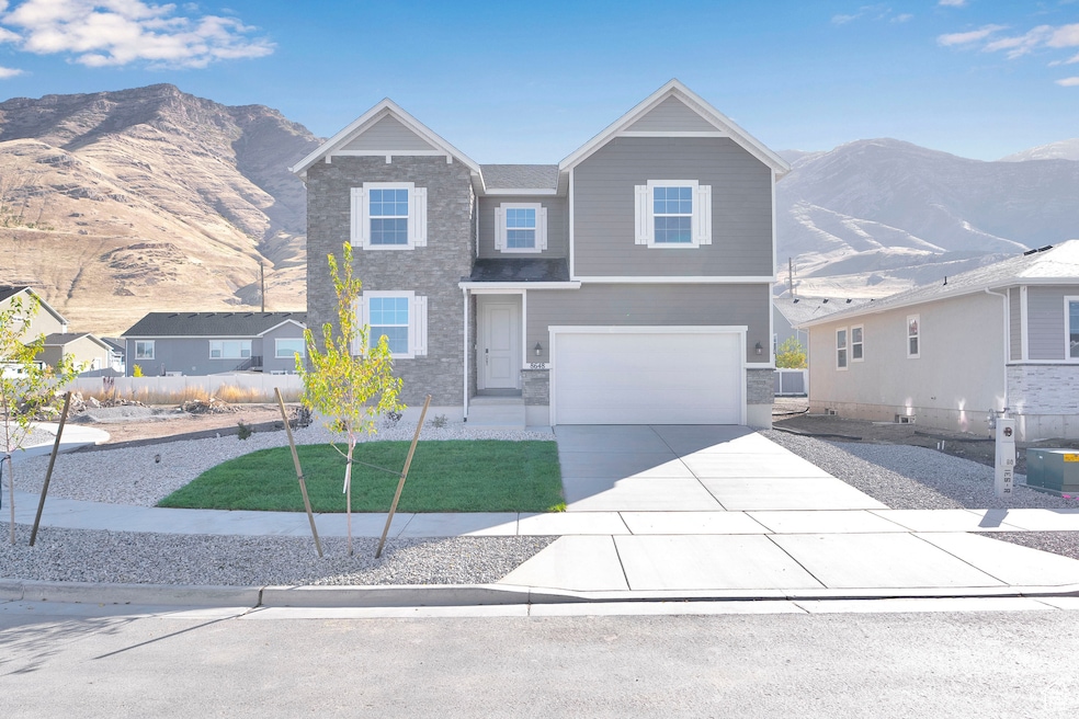 View of front of house with a mountain view, driveway, stone siding, a garage, and a front lawn