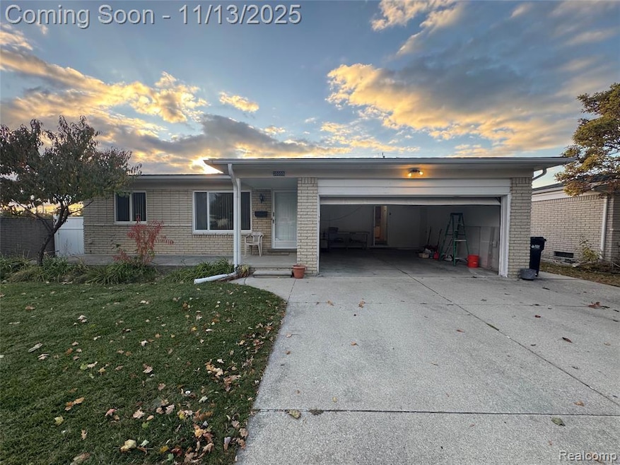 View of front of home featuring brick siding, driveway, a garage, and a front lawn