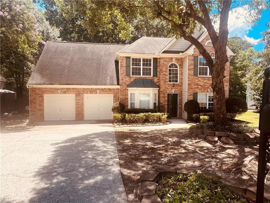 Colonial-style house with roof with shingles, concrete driveway, brick siding, and a garage