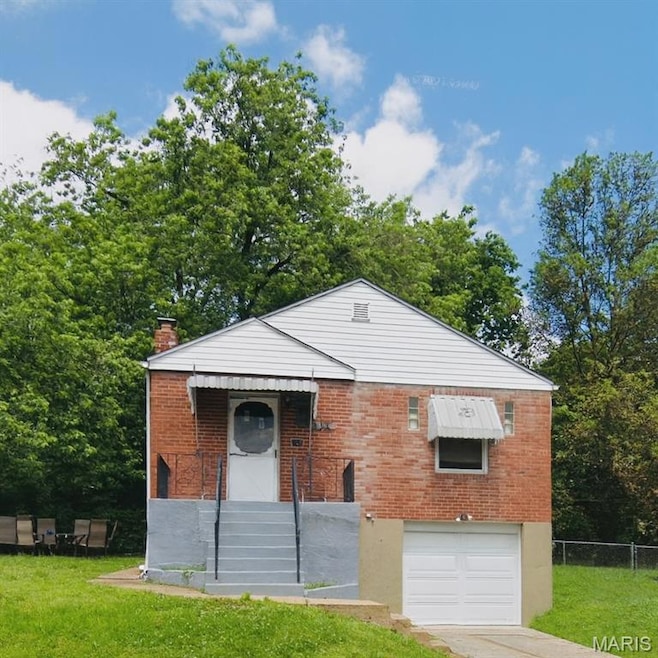 View of front facade featuring an attached garage, a chimney, concrete driveway, and brick siding