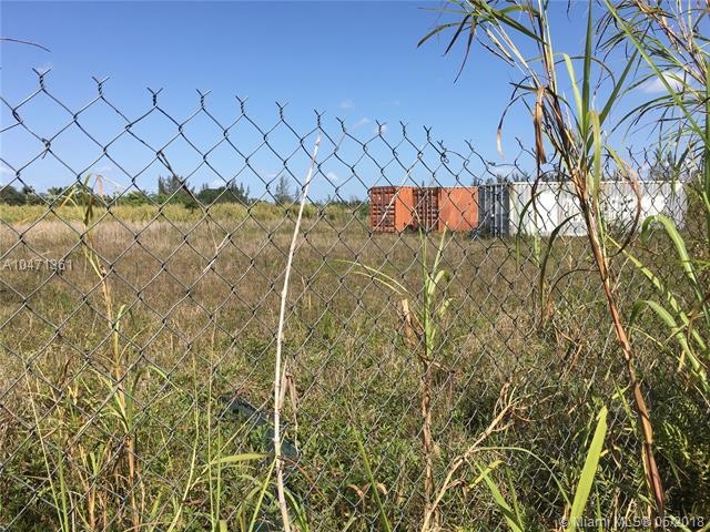 Vacant lot showing fence and containers.