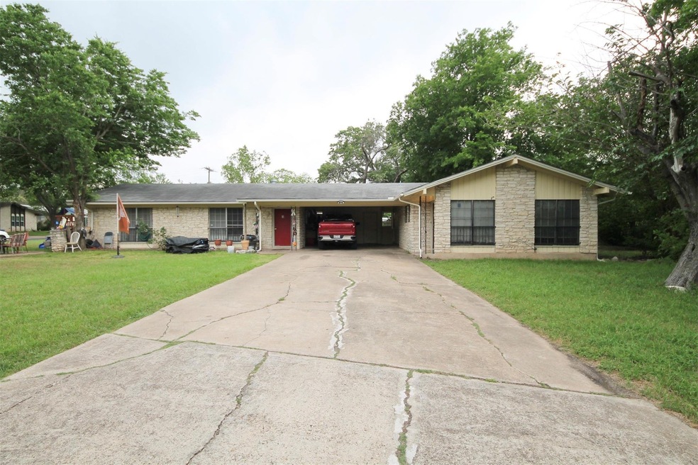 Ranch-style home featuring a front yard, driveway, and an attached carport