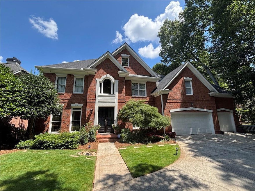 View of front facade featuring brick siding, concrete driveway, a front yard, a garage, and french doors