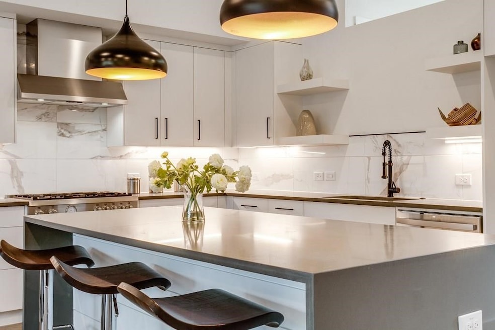 Kitchen with wall chimney exhaust hood, white cabinetry, a breakfast bar, open shelves, and backsplash