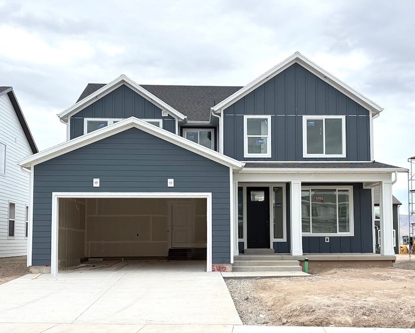 View of front of property featuring board and batten siding, concrete driveway, a porch, and roof with shingles
